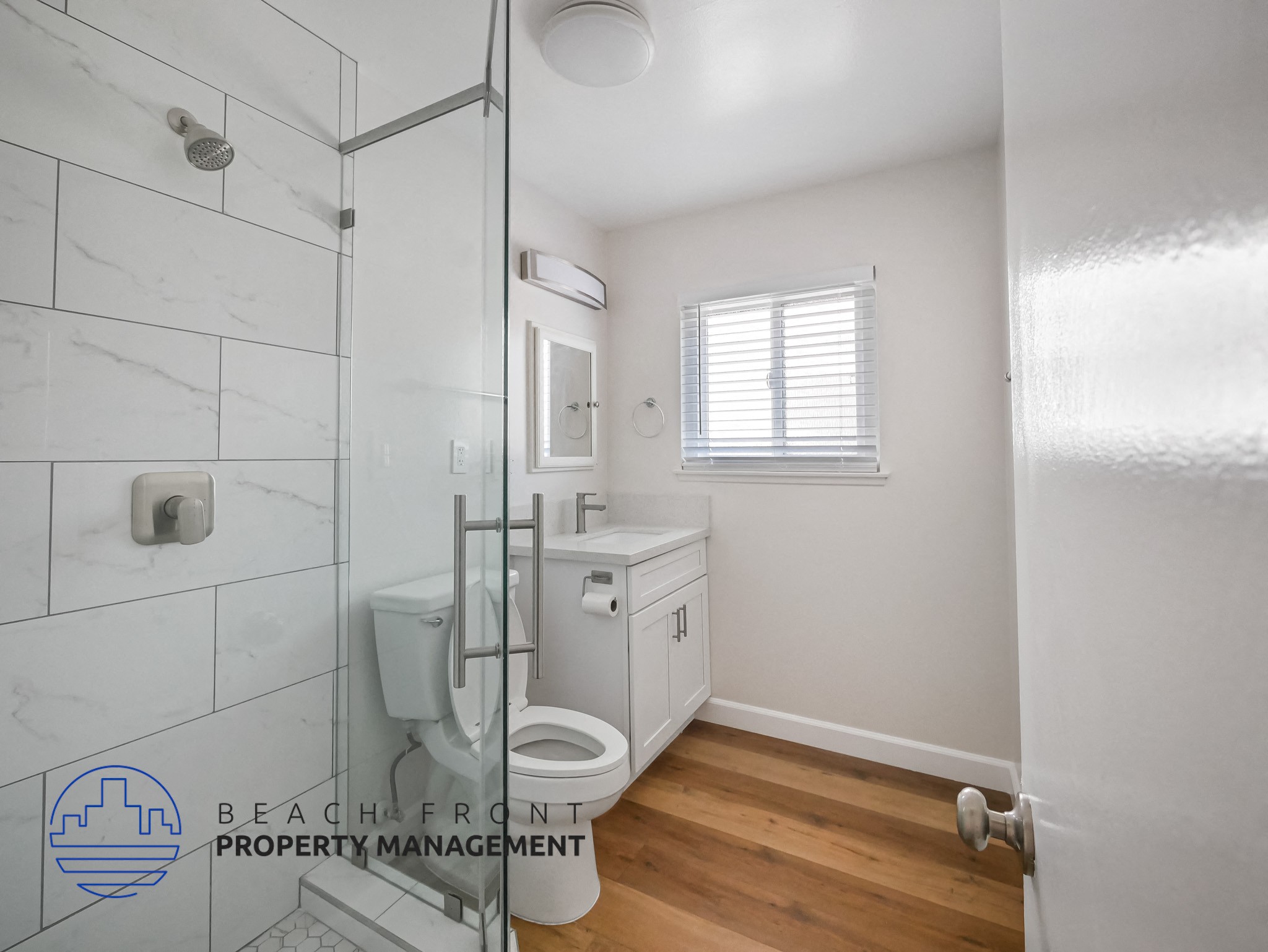 A white bathroom with a toilet, sink, and shower.